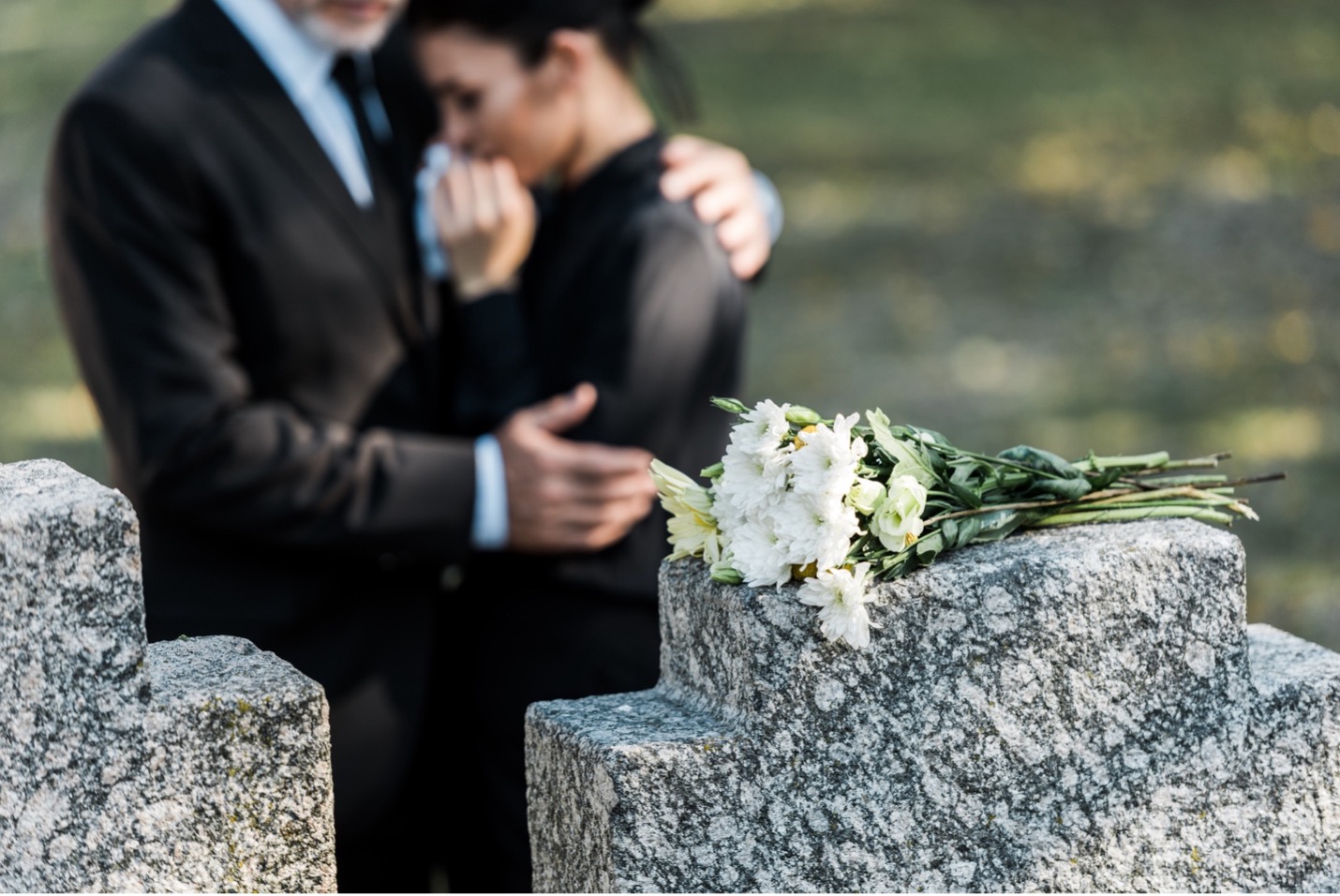 Two family members mourning standing by grave